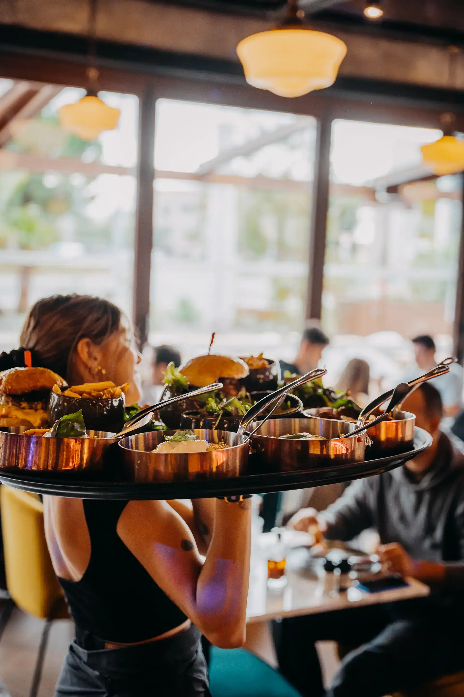 Photo d'une serveuse qui porte un plateau rempli de burgers appetissants